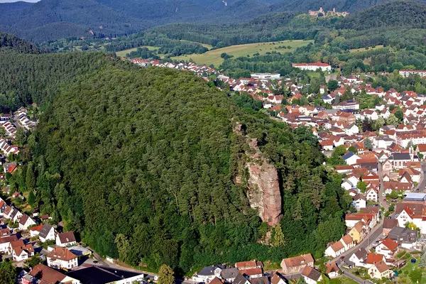 Ein Wald mit einem Felsen und drumherum eine Kleinstadt.