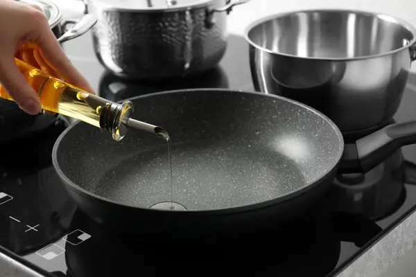 Öl aus einer Glasflasche wird in eine Pfanne geschüttet.