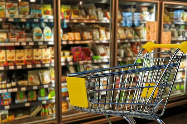 Ein Supermarktkühlregal und im Vordergrund steht ein Einkaufswagen.