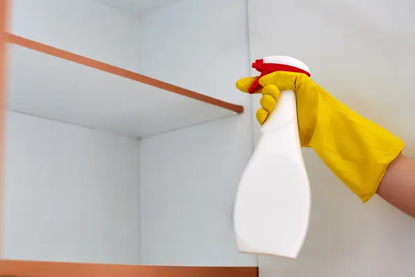 Jemand sprüht einen Küchenschrank ein