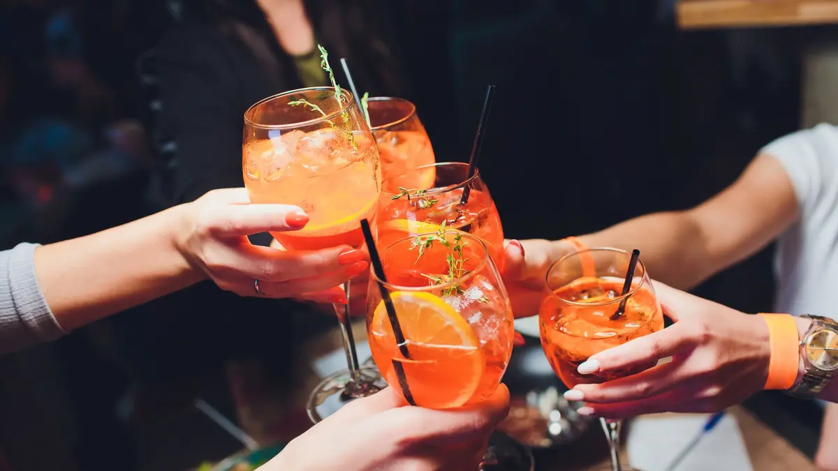Foto von fünf Händen mit Aperol-Gläsern, die anstoßen