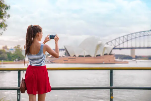 Junge Frau fotografiert Habour Bridge in Sydney.