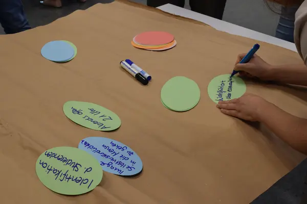 Eine Person schreibt bei einem Workshop etwas auf ein PostIt
