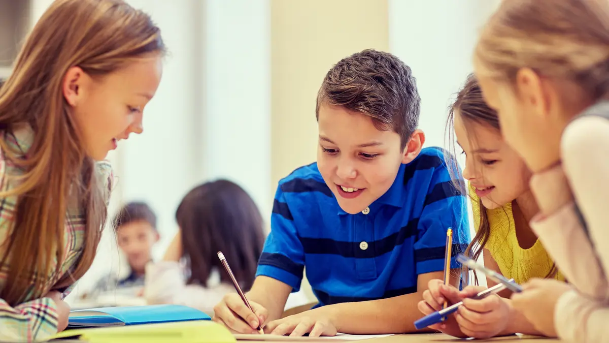 Kinder sitzen am Tisch und machen eine Gruppenarbeit