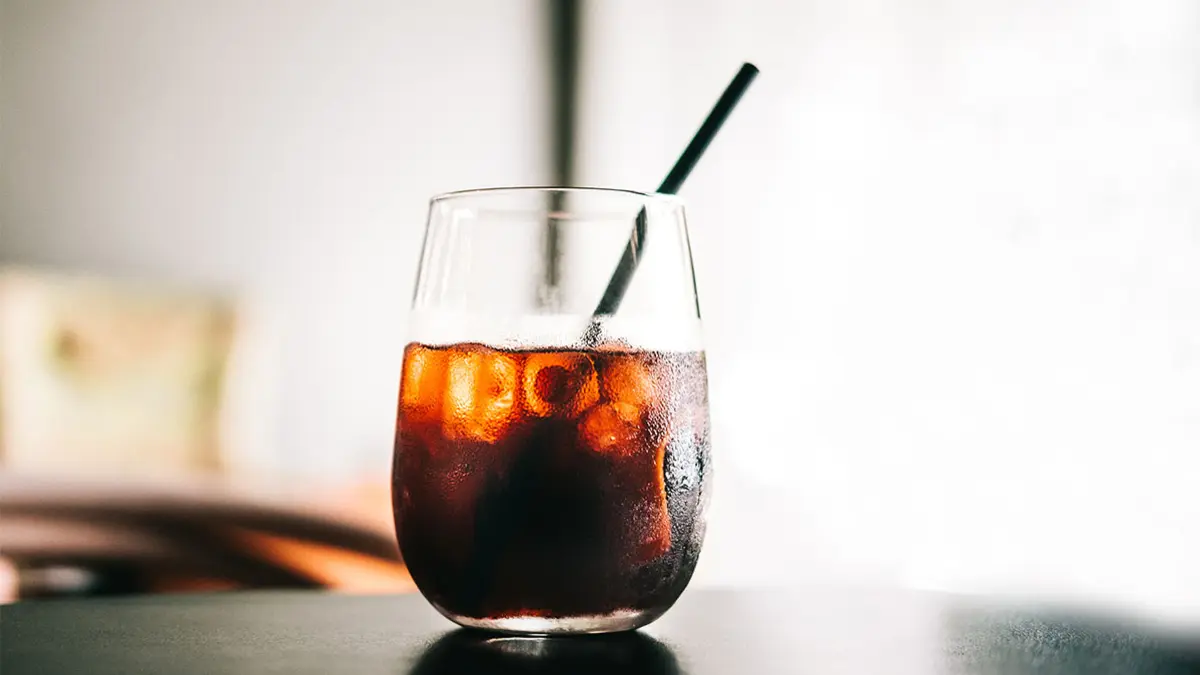 Glas mit Cold Brew Kaffe, Eiswürfeln und Strohhalm