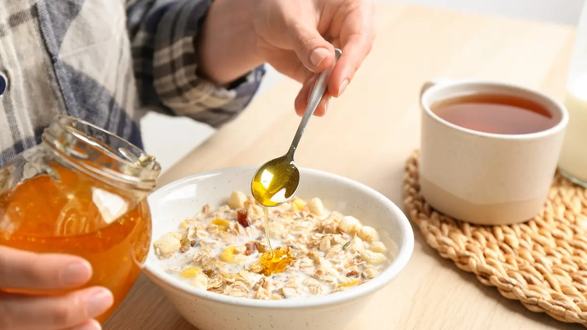 Eine Frau macht Honig in ihr Frühstück.