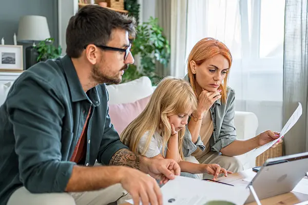 Eine Familie sitzt auf dem Sofa und studiert Unterlagen
