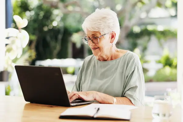 Frau mit weißem Haar sitzt vor Laptop