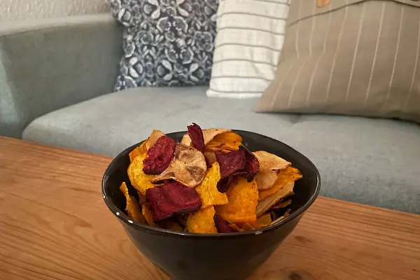 Eine Schüssel mit Gemüsechips steht auf einem Couchtisch.