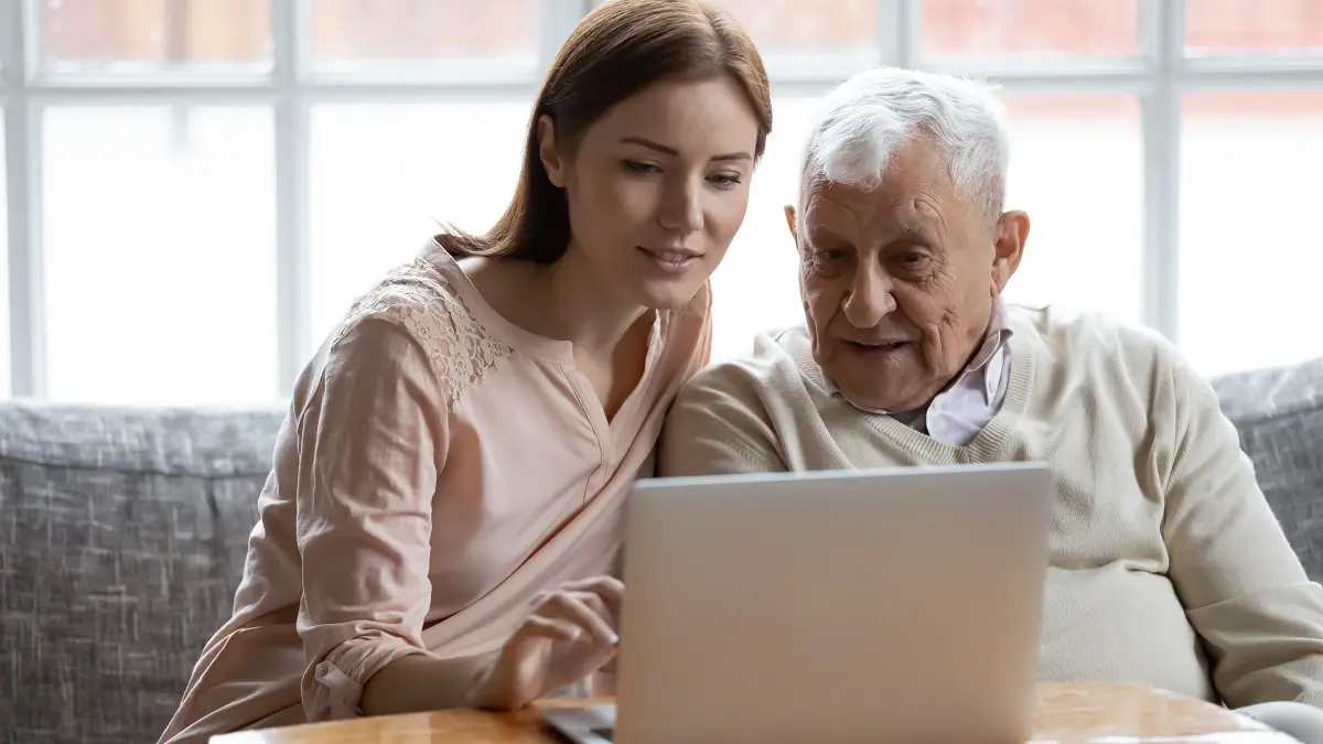 Ein Vater und seine erwachsene Tochter sitzen zusammen vor einem Laptop.