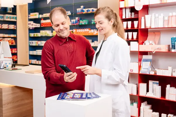 Eine Apothekerin berät einen Kunden zu einer Gesundheitsapp.