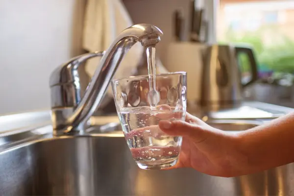 Aus einem Wasserhahn wird frisches Wasser in ein Glas gefüllt