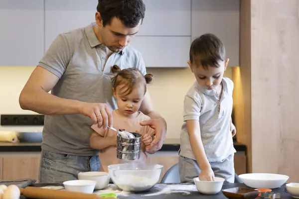 Mann und zwei kleine Kinder backen in der Küche 