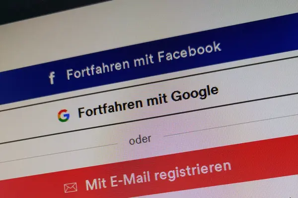 Ein PC-Monitor zeigt den Login-Bereich einer Internetseite mit Buttons für Facebook-Login, Google-Login und Anmeldung per E-Mail