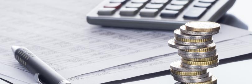 Taschenrechner mit Geldmünzen und Unterlagen