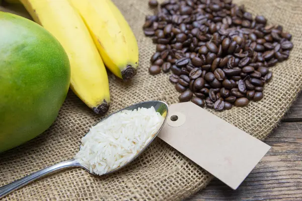 Kaffee, Reis, Bananen und eine Mango liegen auf einem Kaffeesack