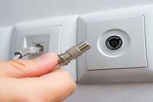 Ein Mann steckt ein Kabel in eine Kabelanschlussdose