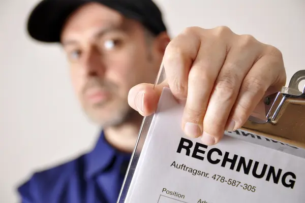 Ein Handwerker hält eine Rechnung in die Kamera