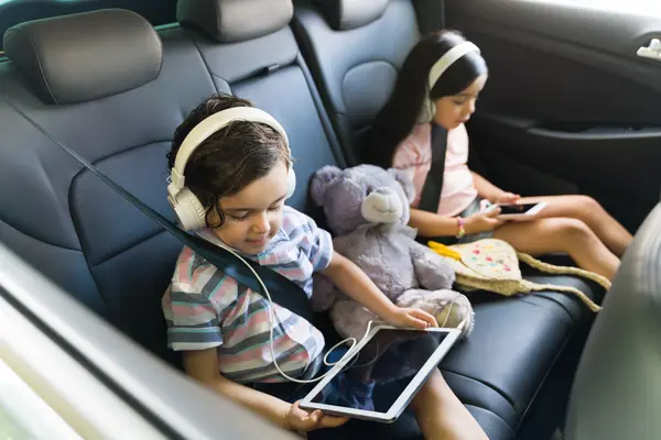 Kinder mit Tablet und Smartphone im Auto
