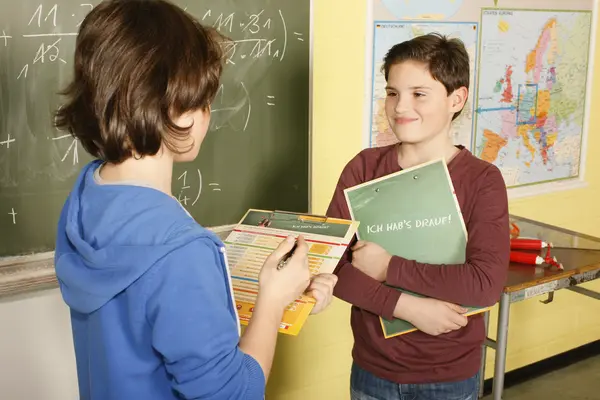 Zwei Kinder sprechen in der Schule miteinander.