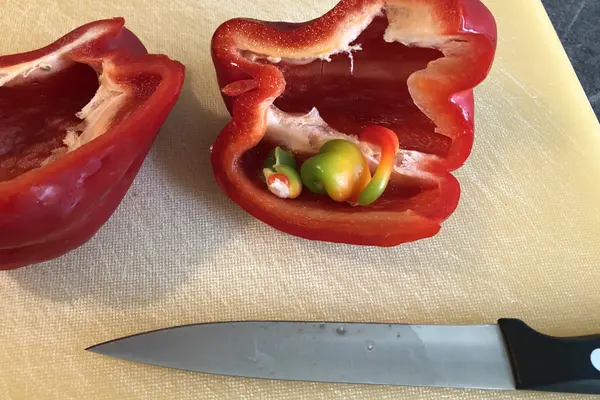 Eine aufgeschnittene Paprika mit kleinen, losen Teilen darin.