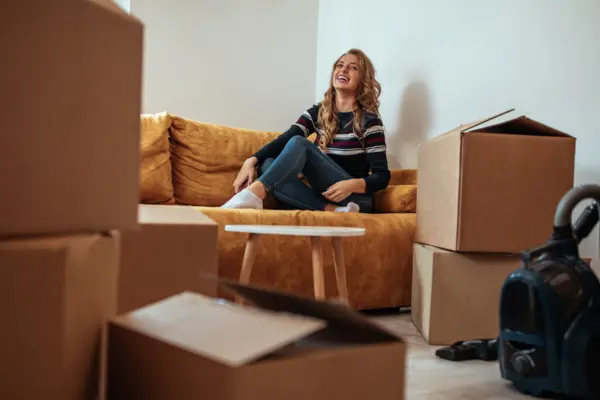 Eine junge Frau sitzt inmitten verschiedener Umzugskartons auf einem Sofa
