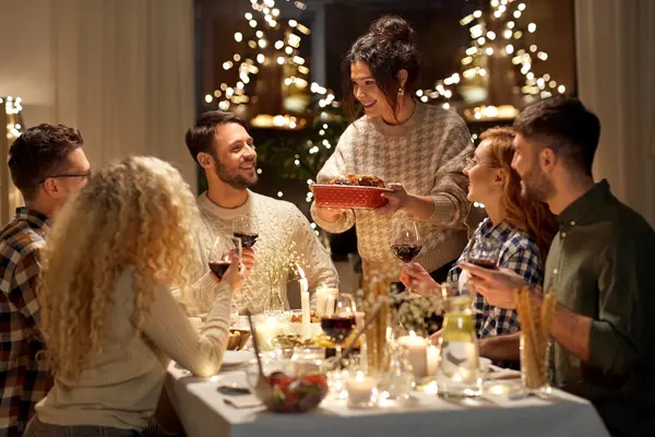 Freunde sitzen gemeinsam am Tisch und genießen ihr Weihnachtsessen