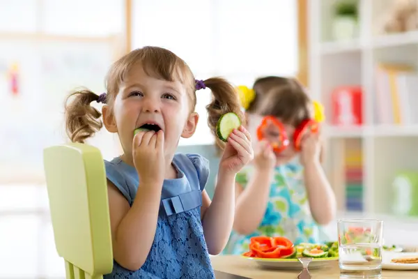 Kita-Kinder essen Gurken und Paprikascheiben