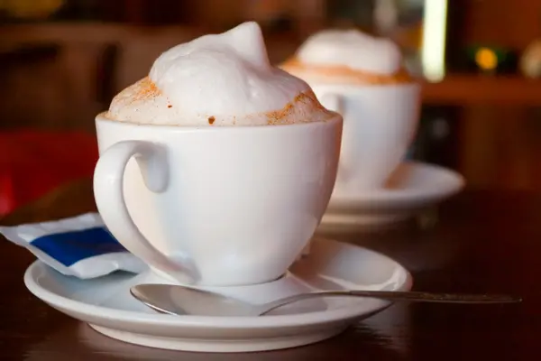Zwei Tassen mit Kaffee, auf denen Milchschaum zu sehen ist
