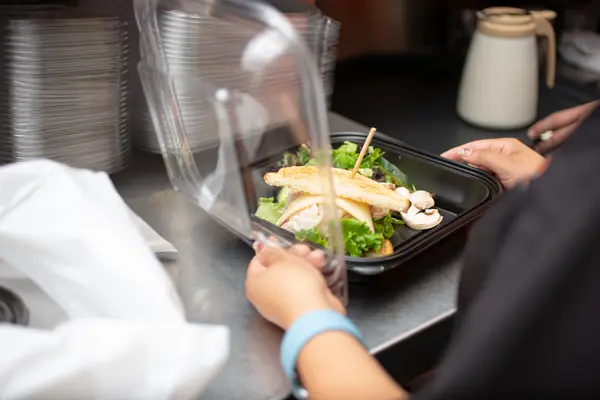Frau verpackt Essen für einen Lieferdienst in einem Einwegbehälter