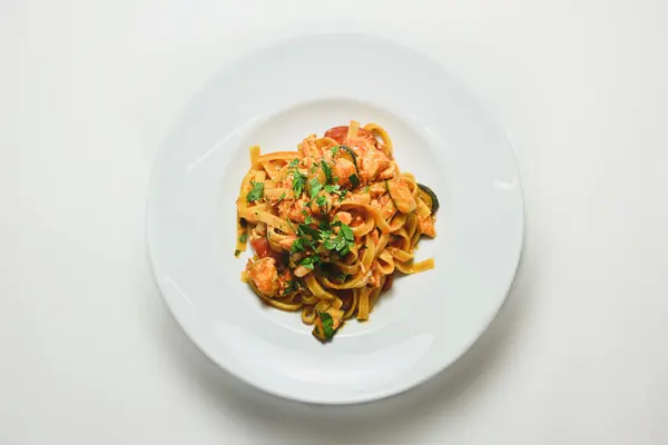 Nudeln mit Zucchini Tomatensauce auf einem weißen Teller