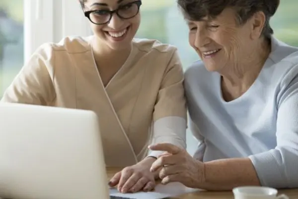 Mutter und Tochter sitzen zusammen vor einem Laptop am Tisch