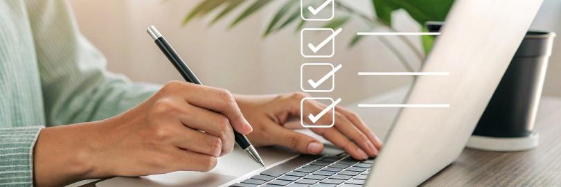 Person arbeitet am Laptop mit Checkliste.