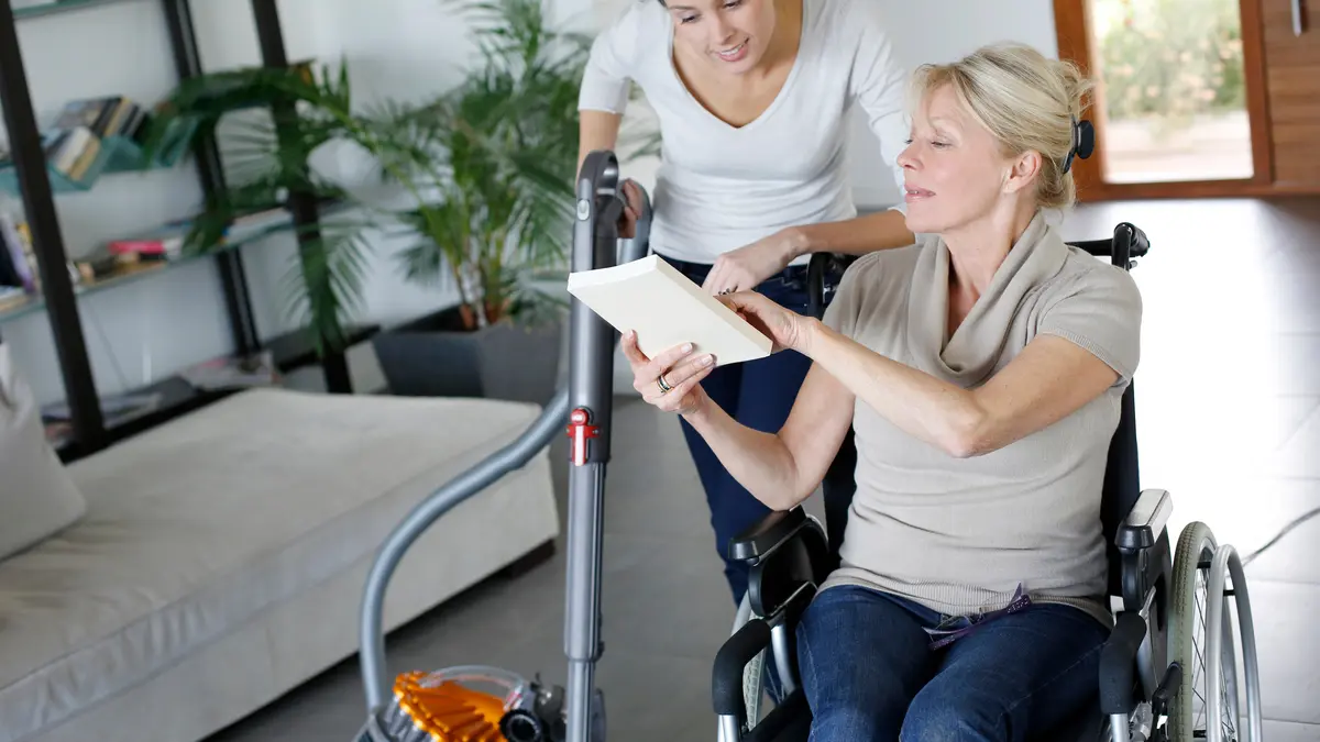Haushaltshilfe hilft Patientin im Rollstuhl