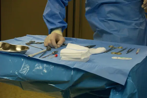 chirurgische Instrumente auf einem OP-Tisch, Hand des Chirurgen greift nach Material