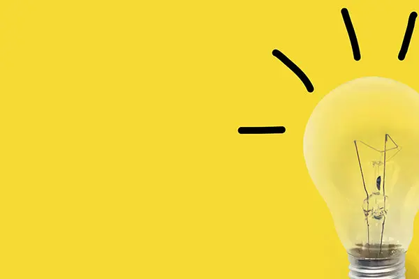 Strahlende Glühlampe vor gelbem Hintergrund - Projekt "Hessen bekämpft Energiearmut"
