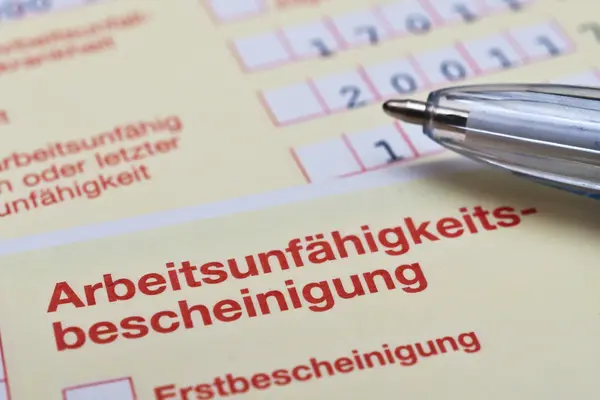 Auf einer Arbeitsunfähigkeitsbescheinigung vom Arzt liegt ein Kugelschreiber.