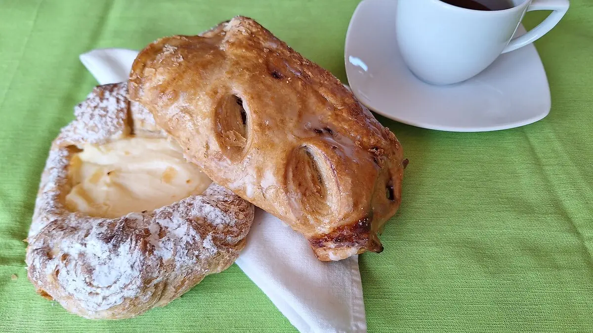 Zwei Gebäckstücke liegen auf einer Serviette, daneben eine Tasse Tee.
