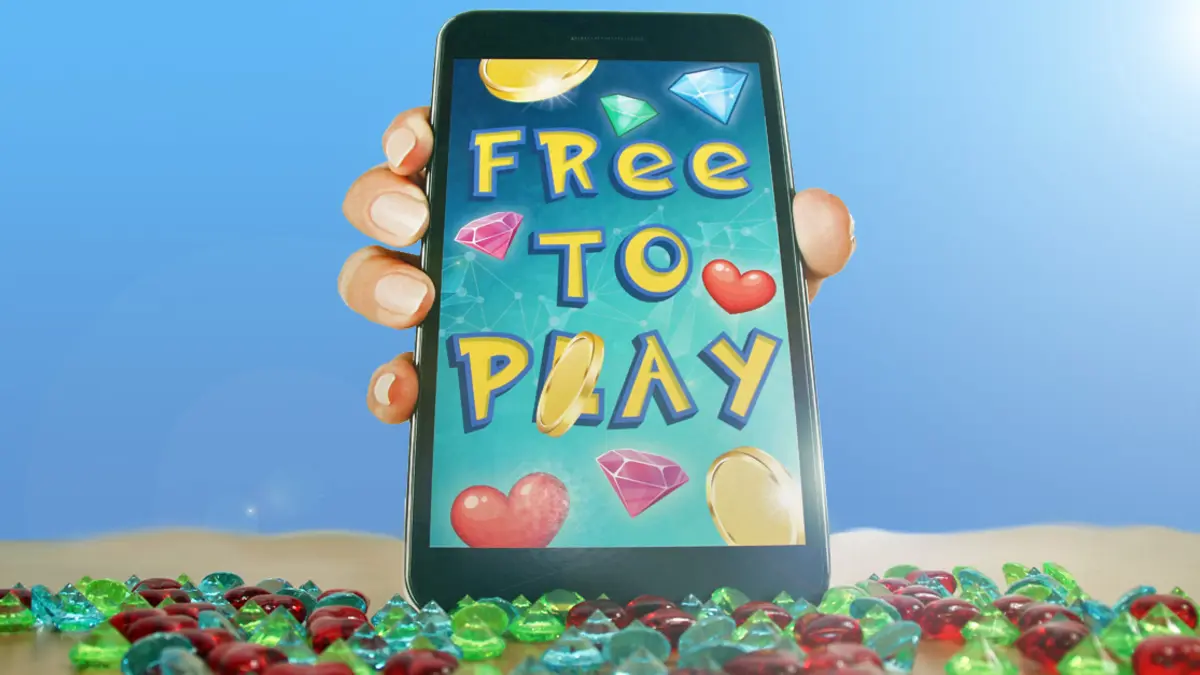 Eine Hand hält ein Smartphone mit der Aufschrift "FREE TO PLAY". Um die Schrift sind viele Münzen und Diamanten zu sehen, das Gerät steht auf einem Sandstrand mit Diamanten.