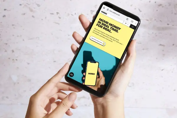 Zwei Hände halten ein Smartphone, auf dem Display ist die Internetseite von Wero zu sehen