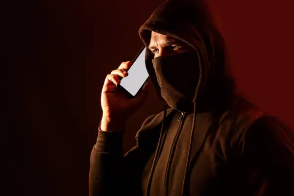 Ein maskierter Mann telefoniert mit einem Smartphone