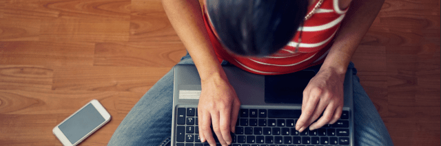 junge Frau auf Holzboden sitzend mit Laptop, von oben fotografiert