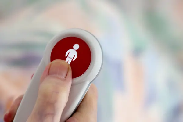 Finger drückt auf Notrufknopf für Senioren