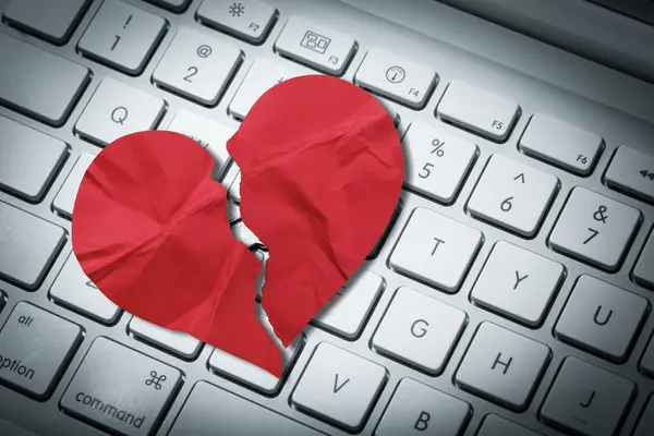 Computertastatur mit einem Papierherz, das zerrissen ist