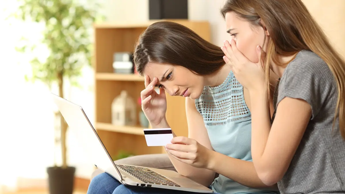 Zwei junge Frauen am Laptop schauen geschockt.