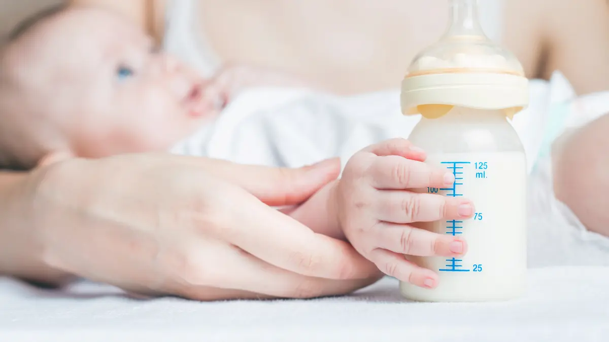 Baby hält ein Fläschchen mit Milch