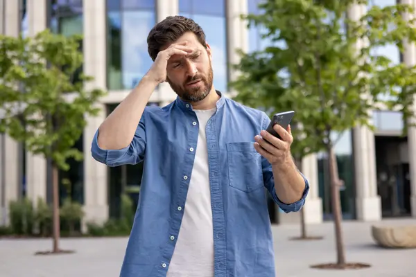 Mann schaut verärgert auf sein Smartphone.