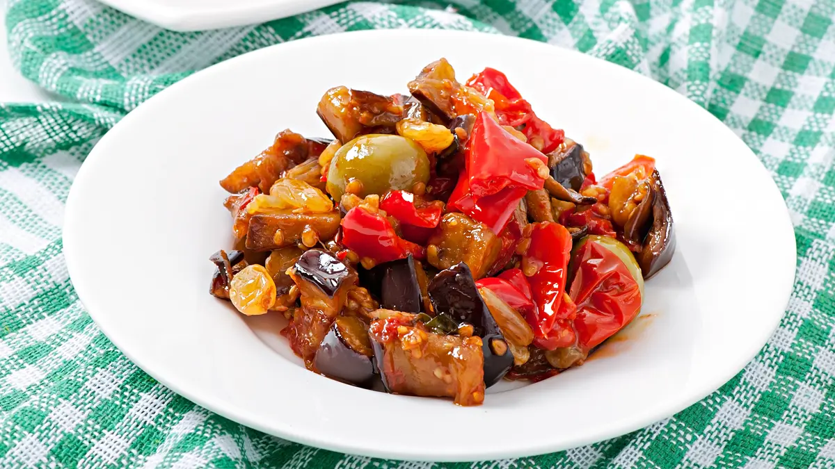 Caponata aus Aubergine, Paprika und Oliven auf einem Teller