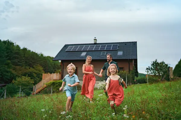Familie auf einer Wiese vor Haus mit Photovoltaikanlage
