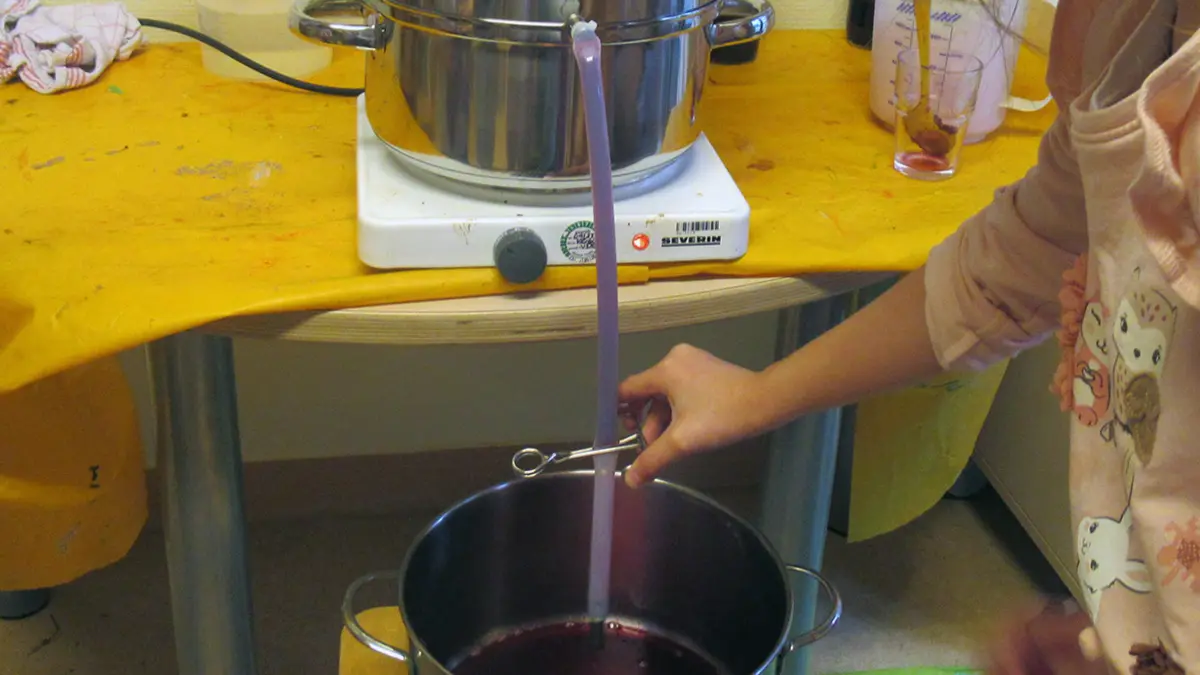 Aus einem Entsafter fließt Traubensaft in einGefäß
